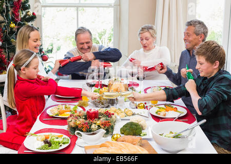 Family pulling christmas crackers at the dinner table Stock Photo