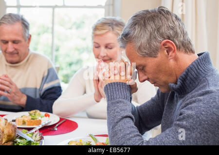 Extended family saying grace before christmas dinner Stock Photo