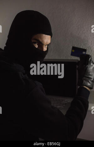 Hacker using debit card and laptop Stock Photo