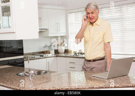 Senior man using his laptop on the phone Stock Photo