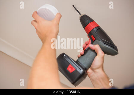 Handyman installing smoke detector Stock Photo
