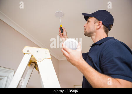 Handyman installing smoke detector Stock Photo