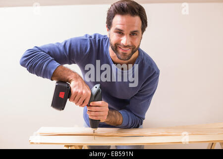 Casual man drilling hole in plank Stock Photo