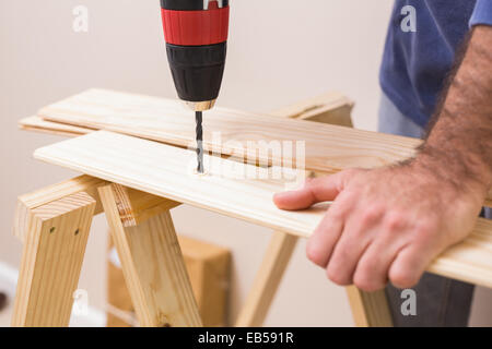 Casual man drilling hole in plank Stock Photo