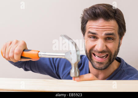 Casual man hammering his finger by accident Stock Photo