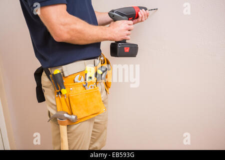 Construction worker drilling hole in wall Stock Photo