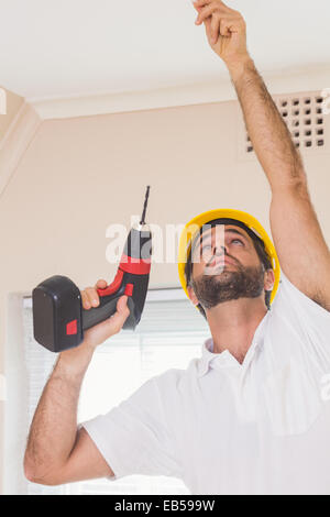 Construction worker drilling hole in ceiling Stock Photo