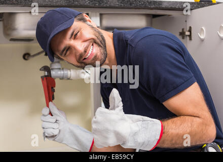 Plumber smiling at the camera fixing under the sink Stock Photo