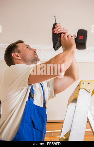 Handyman using a cordless drill to the ceiling Stock Photo