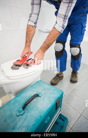 Plumber putting his tools on toilet Stock Photo