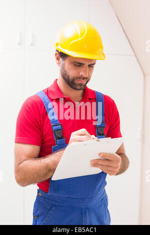 Construction worker taking notes on clipboard Stock Photo