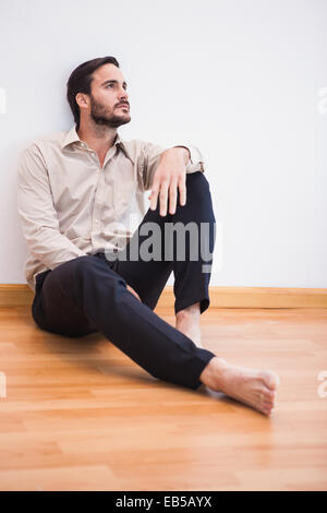 Casual thoughtful man leaning against wall looking up Stock Photo
