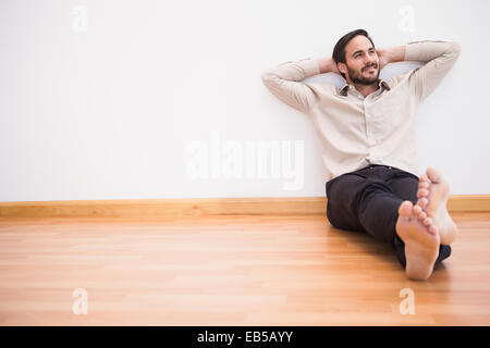 Thoughtful man leaning against wall with crossed arms Stock Photo