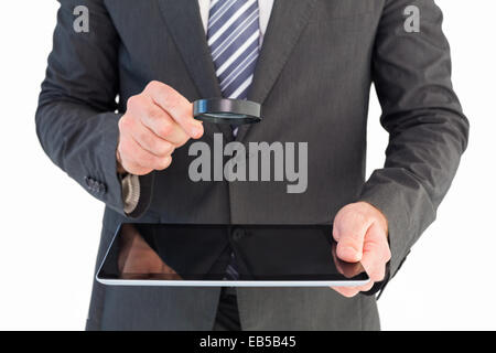Businessman looking at tablet with magnifying glass Stock Photo