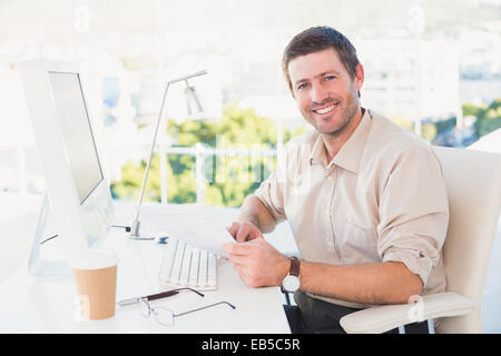 Smiling businessman looking at document at his desk Stock Photo