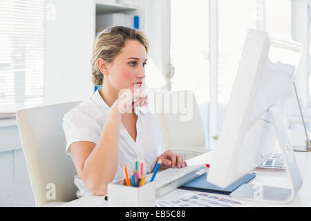 Focused blonde editor working at her desk Stock Photo
