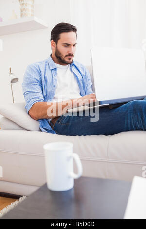 Man lying on sofa using laptop Stock Photo