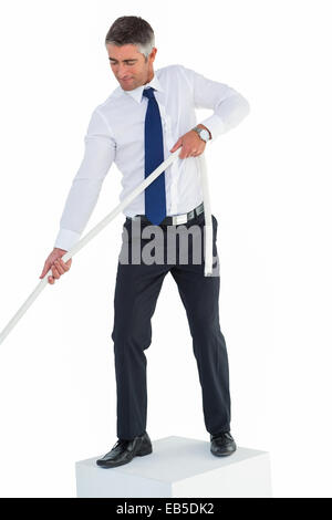 Businessman standing on cube pulling rope Stock Photo