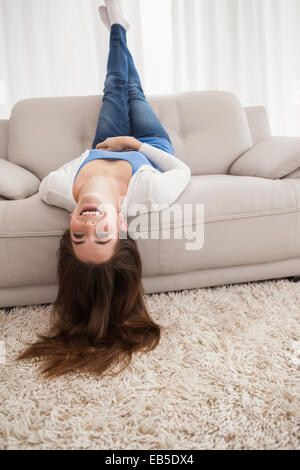 Pretty brunette lying upside down on couch Stock Photo