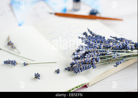 Close up of a bunch of lavender on a notebook, on white table, with blurry pen, ink, bunting Stock Photo
