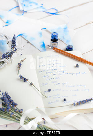 Notebook with words about summer, ink, pen, bunting and lavender on a white table Stock Photo