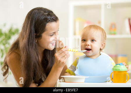 Beautiful young woman feeds her son baby Stock Photo