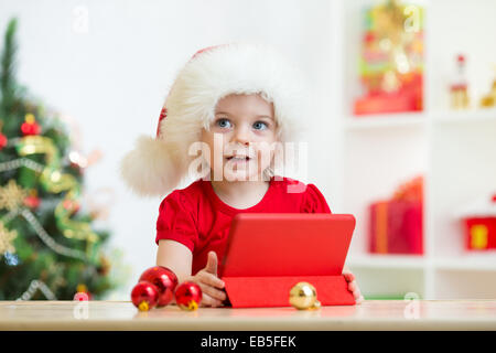 toddler girl in christmas hat with tablet pc Stock Photo