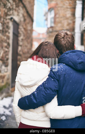 Back view of young man and woman in winterwear embracing outdoors Stock Photo