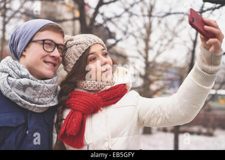 Affectionate young dates in casual winterwear taking photo of themselves outdoors Stock Photo