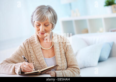 Senior woman making notes in notepad Stock Photo