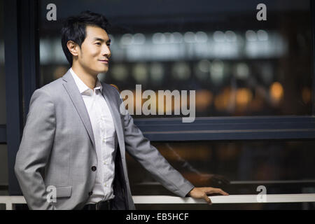 Young businessman standing by window Stock Photo