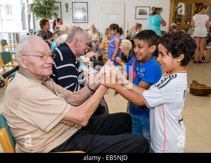 Two six-year-old boys from a kindergarten group seek contact to a ninety-year-old senior in a retirement home Stock Photo