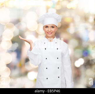 smiling female chef holding something on hand Stock Photo