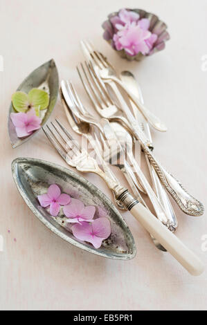 vintage cutlery and baking tins with hydrangea flowers on a cream distressed painted wooden board Stock Photo