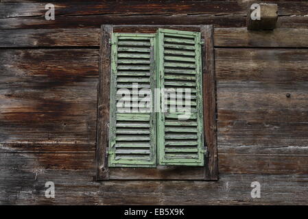 Vintage pastel green wooden shuttered window blind - Alter, verwitterter pastell-grüner Fensterladen an Bauernhaus Stock Photo