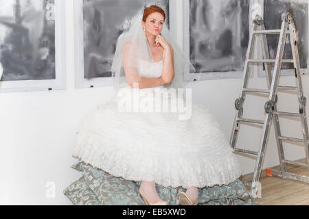 Bride in the artist sat on pillows and lost in thought Stock Photo
