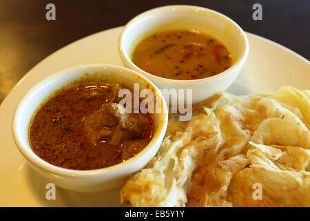 Roti Canai served in Kuala Lumpur, Malaysia. The traditional dish is served with chicken curry and dal. Stock Photo