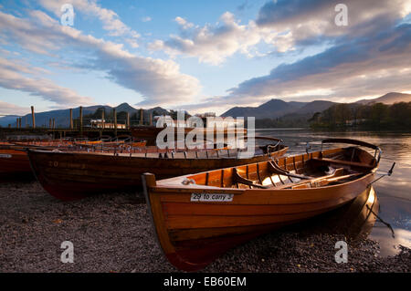 Rowing boats and the Derwent Launch, moored as the sun sets over Derwent Water on the outskirts of Keswick Stock Photo