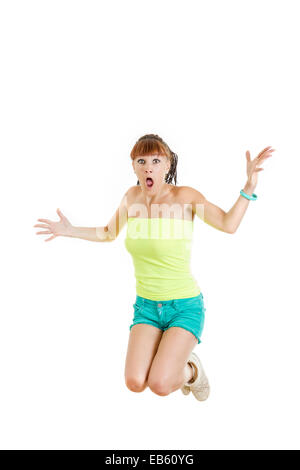 Shocked and surprised beautiful cute young woman or girl in blank green t-shirt and shorts jumps with face expression over white Stock Photo