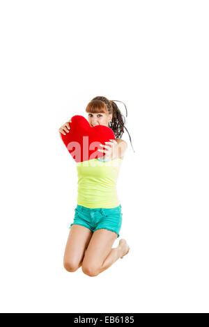 Teen girl in love jumping of joy holding red heart wearing shorts barefoot Stock Photo