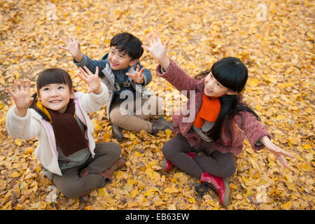 Three children catching falling leaves Stock Photo