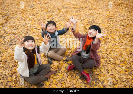 Three children catching falling leaves Stock Photo