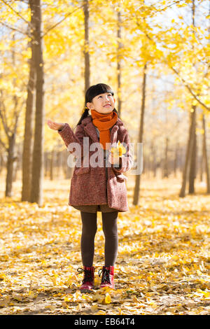 Little girl catching falling leaves Stock Photo
