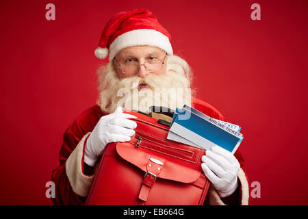 Santa Claus with red leather suitcase and airline tickets Stock Photo