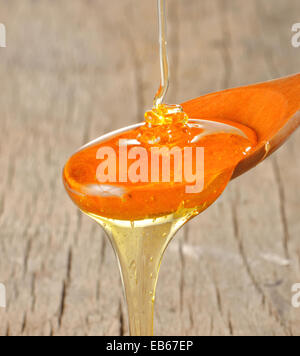 Honey dripping from a wooden honey spoon Stock Photo