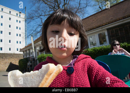Little girl eating white bread sandwich Stock Photo