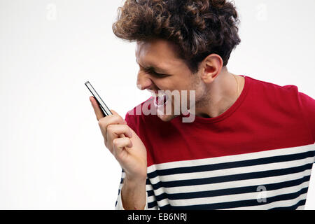 Angry man shouting at smartphone over gray background Stock Photo