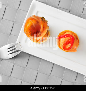 a plate with some different volauvents, one filled with smoked salmon and the other one filled with red pepper and cheese sauce, Stock Photo