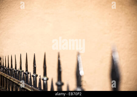 A wrought-iron fence with wall behind. Stock Photo