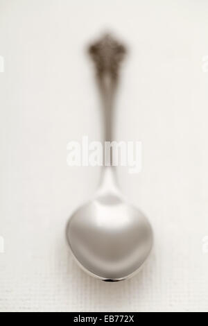 Old silver spoon with selective focus and shallow depth of field on white kitchen tablecloth Stock Photo